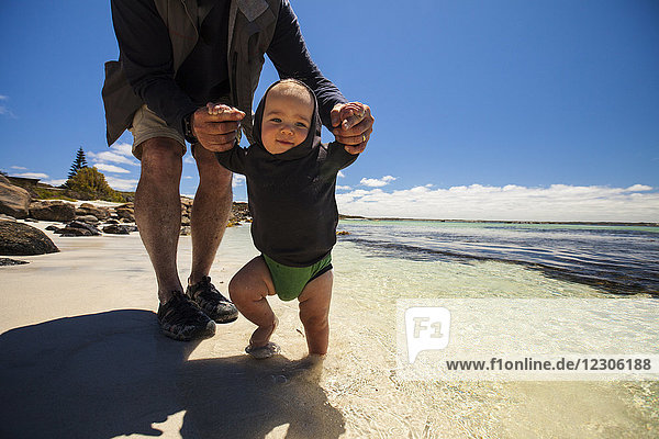 Vorderansicht des Großvaters  der mit einem kleinen Jungen am Strand spielt