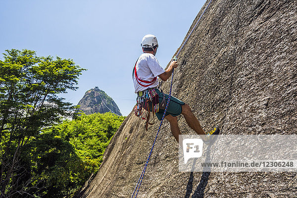 Side view of adventurous man rock climbing Morro da Urca next to the Sugarloaf Mountain  Rio de Janeiro  Brazil