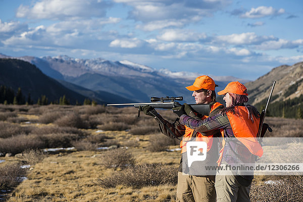 Side view shot of female hunter teaching male hunter about operating rifle