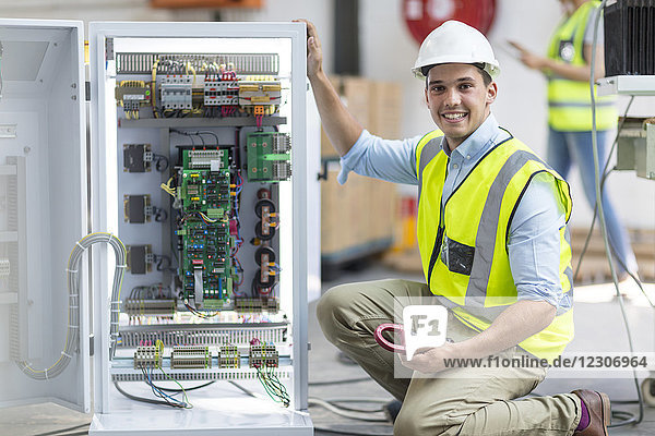 Porträt eines lächelnden Technikers bei der Arbeit an einer Box mit Leiterplatten