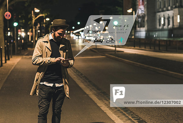 Young man on street at night with data emerging from smartphone