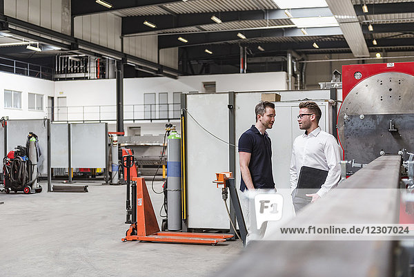 Two men standing and talking on factory shop floor