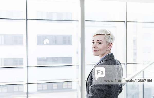 Portrait der Geschäftsfrau im Bürogebäude an der Glasfront