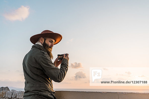 Italien  Sardinien  Mann fotografiert mit Kamera bei Sonnenuntergang