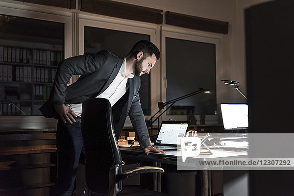 Businessman standing in office at night looking at tablet