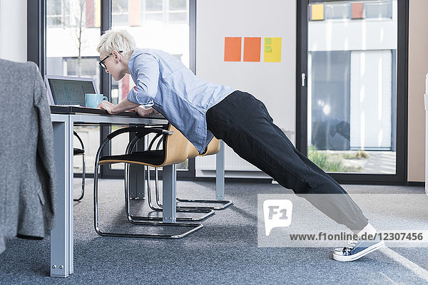 Businesswoman in office doing push ups on desk