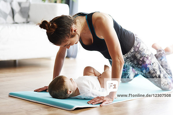 Mother with baby exercising on yoga mat at home