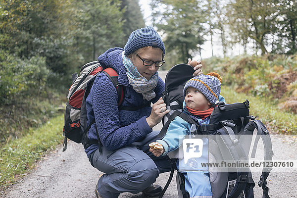 Sohn isst Brot  sitzt in seinem Rückenkorb  neben seiner Mutter während des Wanderns.