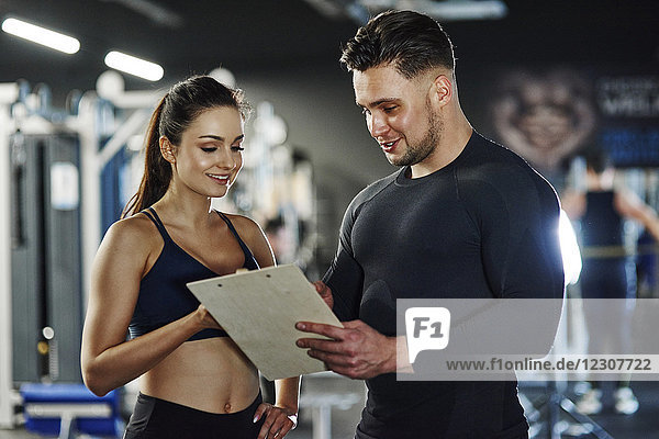 Personal trainer talking to woman in gym