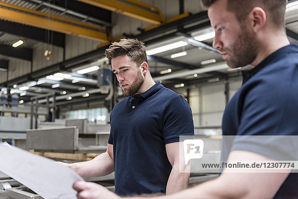 Two men looking at plan in factory