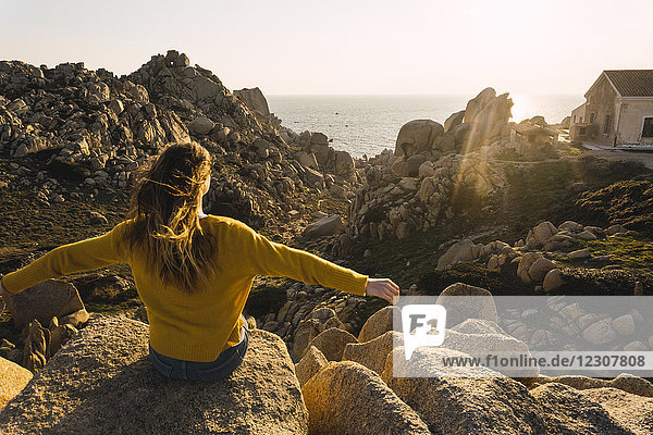 Italien  Sardinien  Frau auf einer Wanderung auf dem Felsen an der Küste sitzend