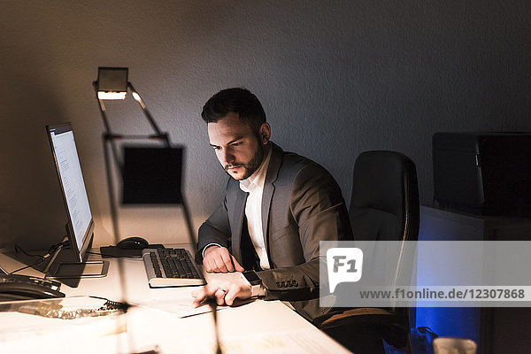 Businessman working on desk in office at night