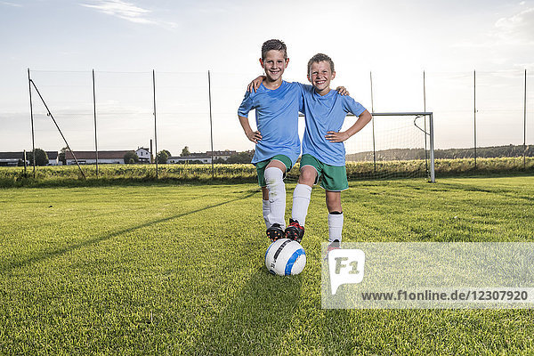 Lächelnde junge Fußballspieler umarmen sich auf dem Fußballplatz