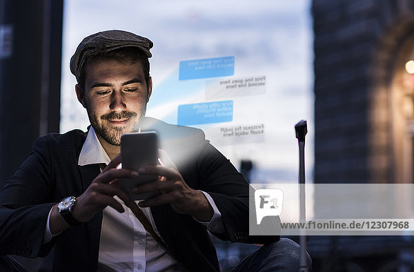 Junger Mann in der Abenddämmerung im Freien mit Text aus dem Smartphone