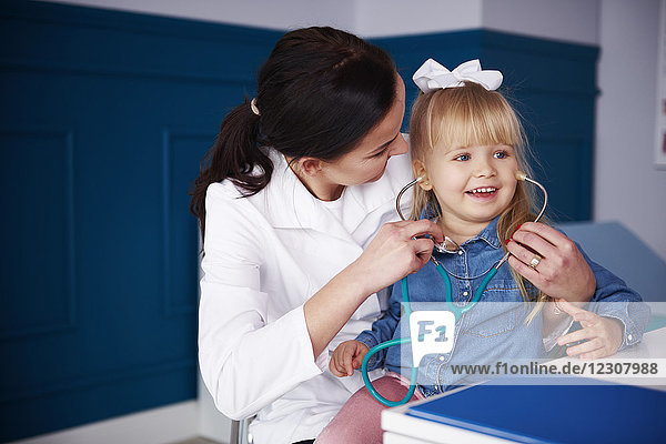Arzt und Mädchen beim Spielen mit dem Stethoskop in der Praxis