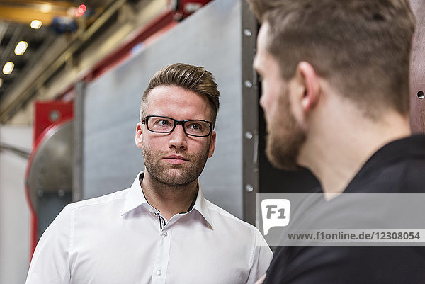 Portrait of businessman looking at employee in factory