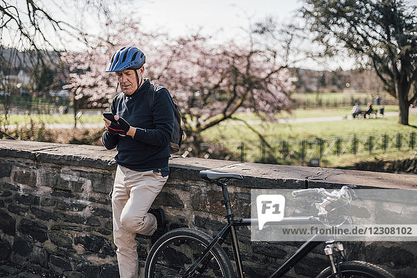 Senior Mann mit Fahrradhelm mit Smartphone