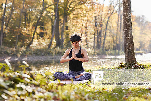 Mittlere erwachsene Frau im Wald praktiziert Yoga  Meditation