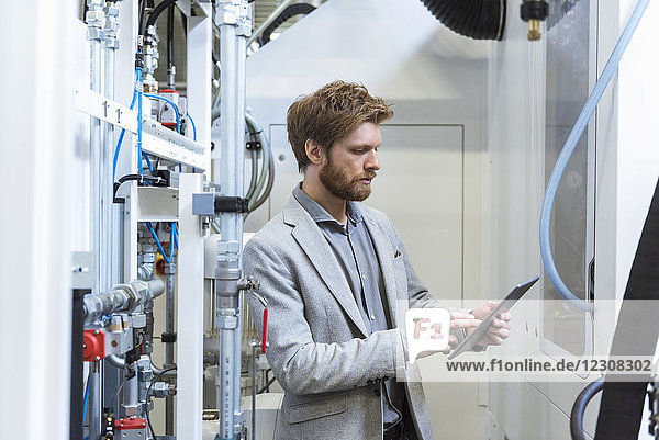 Businessman using tablet at machine in modern factory