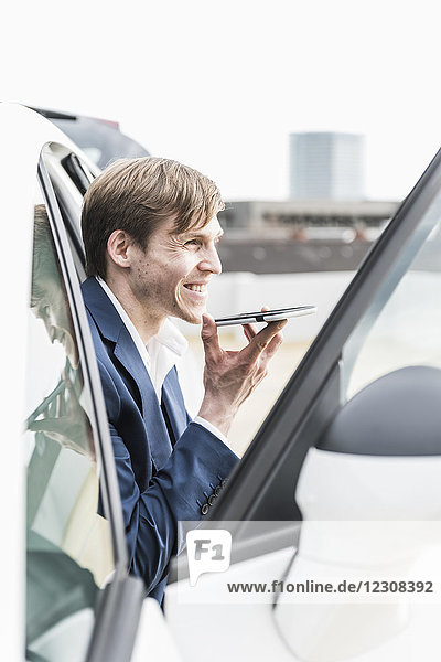 Lächelnder Geschäftsmann mit Smartphone im Auto