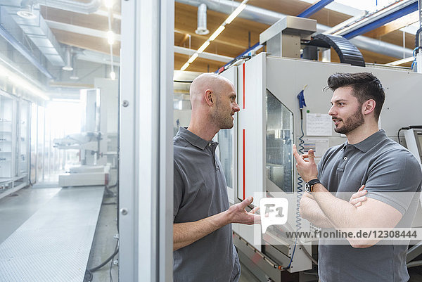 Zwei Männer diskutieren an der Maschine in der modernen Fabrik