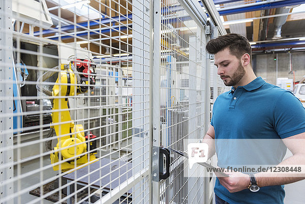 Mann mit Klemmbrett am Industrieroboter in der modernen Fabrik
