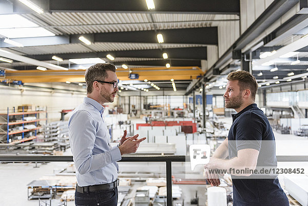 Two men talking on factory shop floor