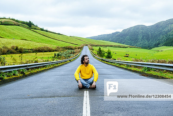 Azoren  Sao Miguel  Mann auf einer leeren Straße sitzend