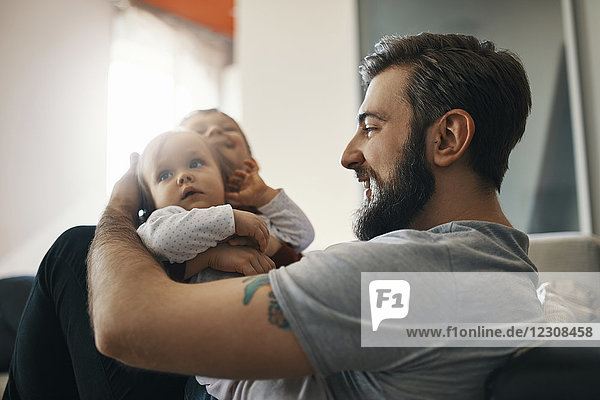 Happy father with baby girl and little son together at home