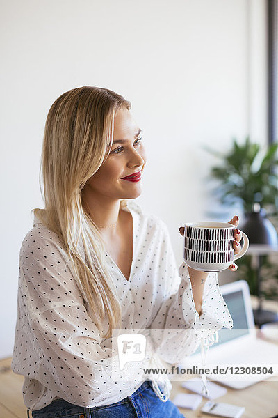 Young woman working in office  taking a break  drinking coffee