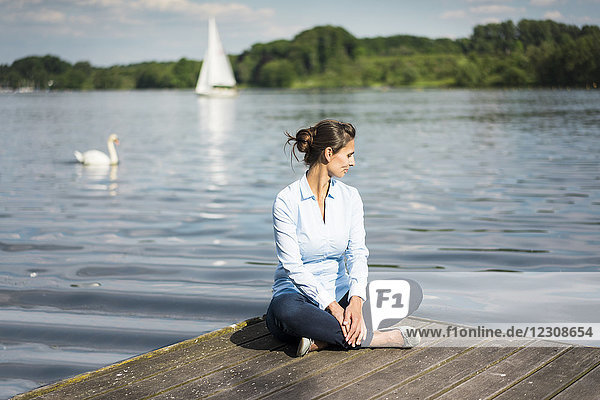 Relaxed woman sitting on jetty at a lake
