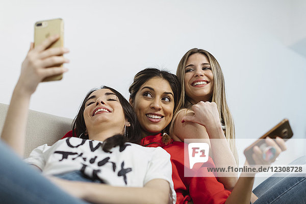 Fröhliche junge Frauen im Büro mit dem Handy