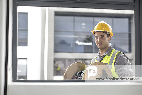 Portrait of construction worker carrying cable drum