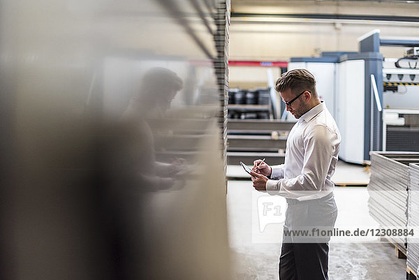 Businessman using tablet on factory shop floor