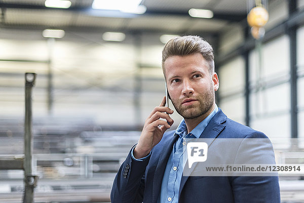 Portrait of confident businessman on cell phone in factory