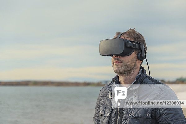 Man wearing VR glasses at lakeshore