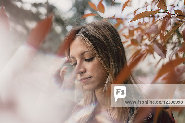 Portrait of young woman in between autumn leaves