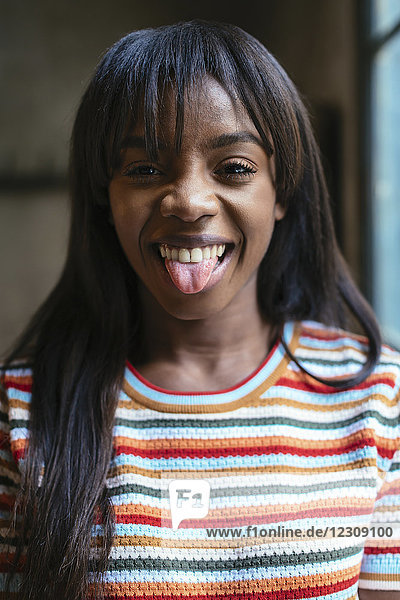 Portrait of laughing young woman sticking out tongue