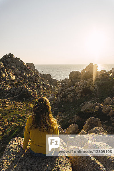 Italien  Sardinien  Frau auf einer Wanderung auf dem Felsen an der Küste sitzend