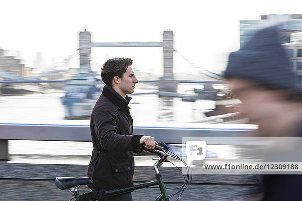 UK  London  businessman pushing bicycle in the city