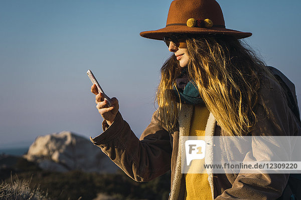 Italien  Sardinien  Frau auf Wanderung mit Blick aufs Handy