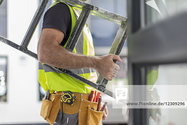 Close-up of construction worker carrying ladder