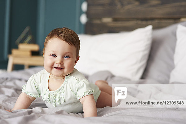 Porträt eines glücklichen Babys  das zu Hause auf dem Bett liegt.