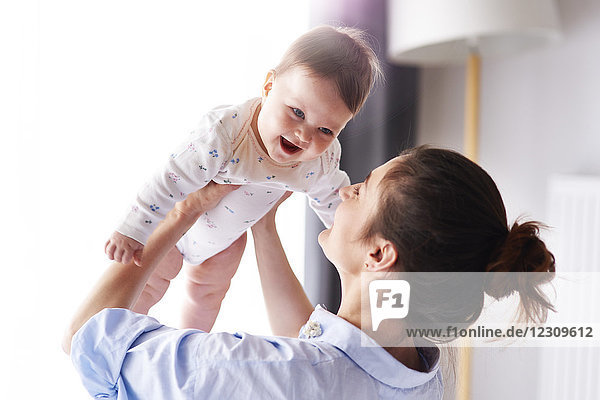 Glückliche Mutter trägt ihr Baby zu Hause.