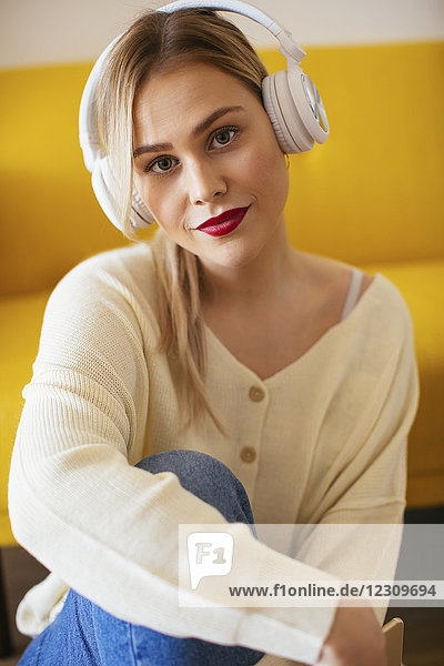 Blonde Frau mit Kopfhörer über Smartphone zu Hause