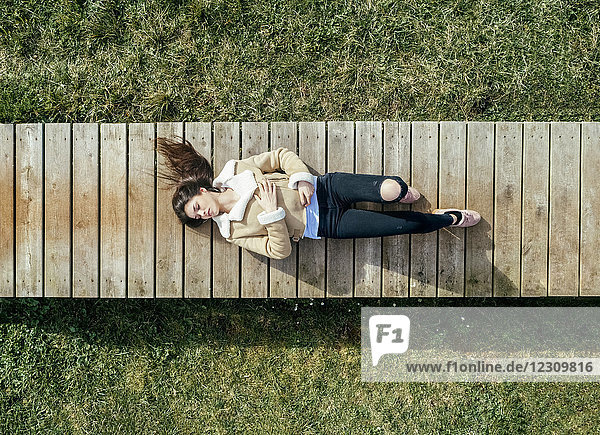 Top view of a young woman lying on boardwalk
