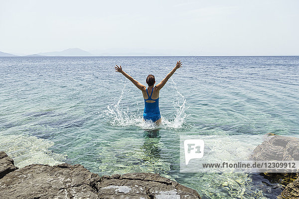 Griechenland  Lefokastro  Frau springt ins Wasser  erhobene Arme