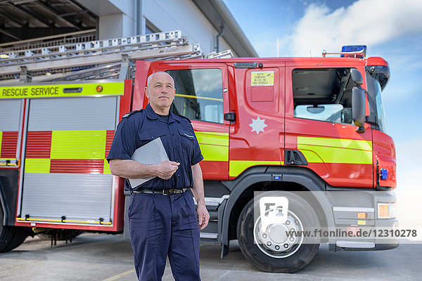 Portrait of fire chief in fire station with fire engine