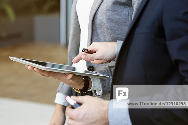 Geschäftsfrau und Mann im Büro mit digitalem Tablet  mittlerer Abschnitt