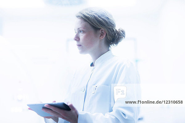 Radiologist  holding digital tablet  looking away